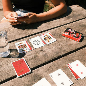 Playing cards laid out on a wooden picnic table.